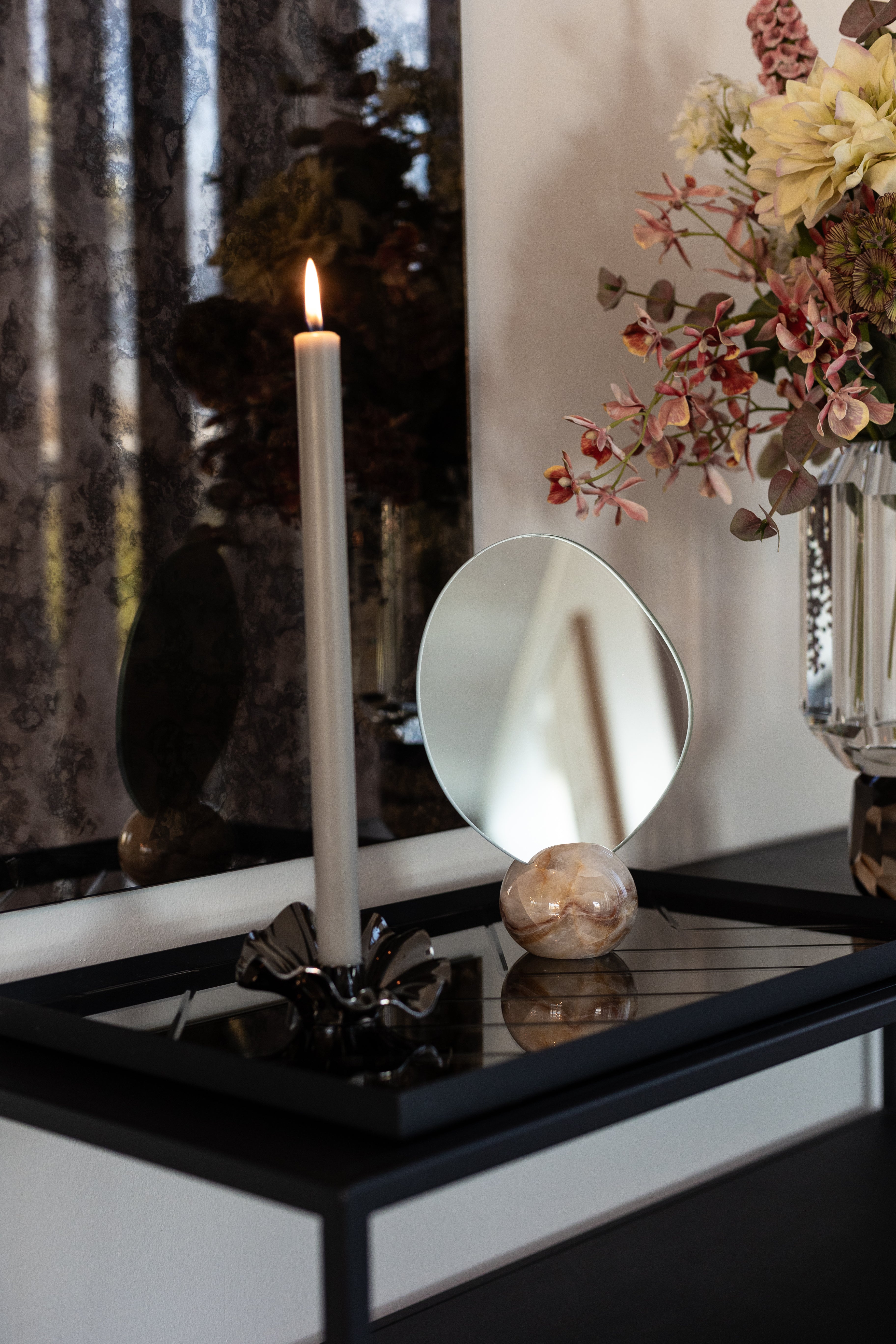 Asta bordspejlet med marmorfod i lyse og orange nuancer, stylet på et konsolbord med andre produkter fra Specktrum.