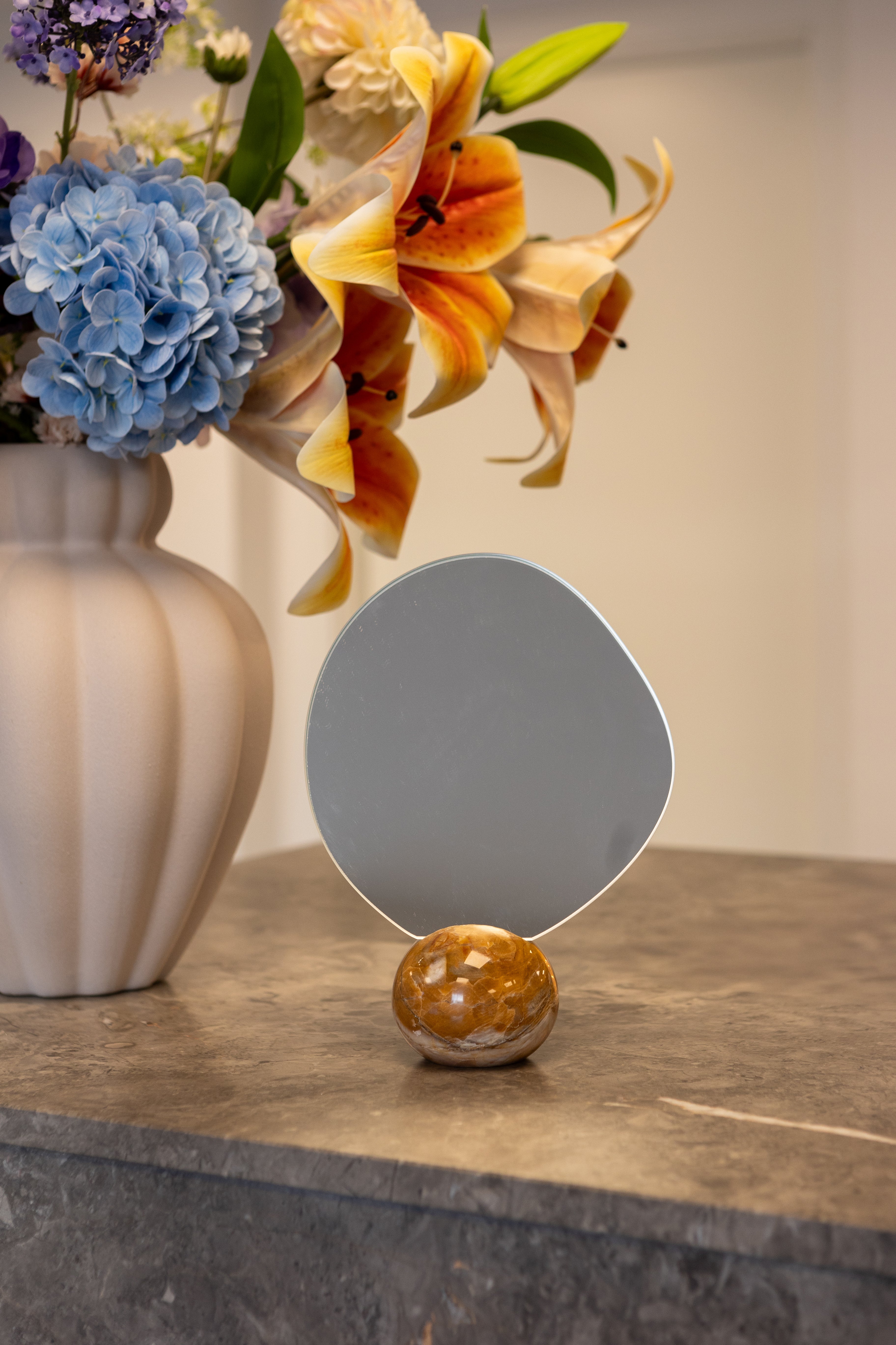 Asta bordspejl med unik marmorfod i orange og beige nuancer. Stylet ved siden af en Penelope vase med en stor buket.