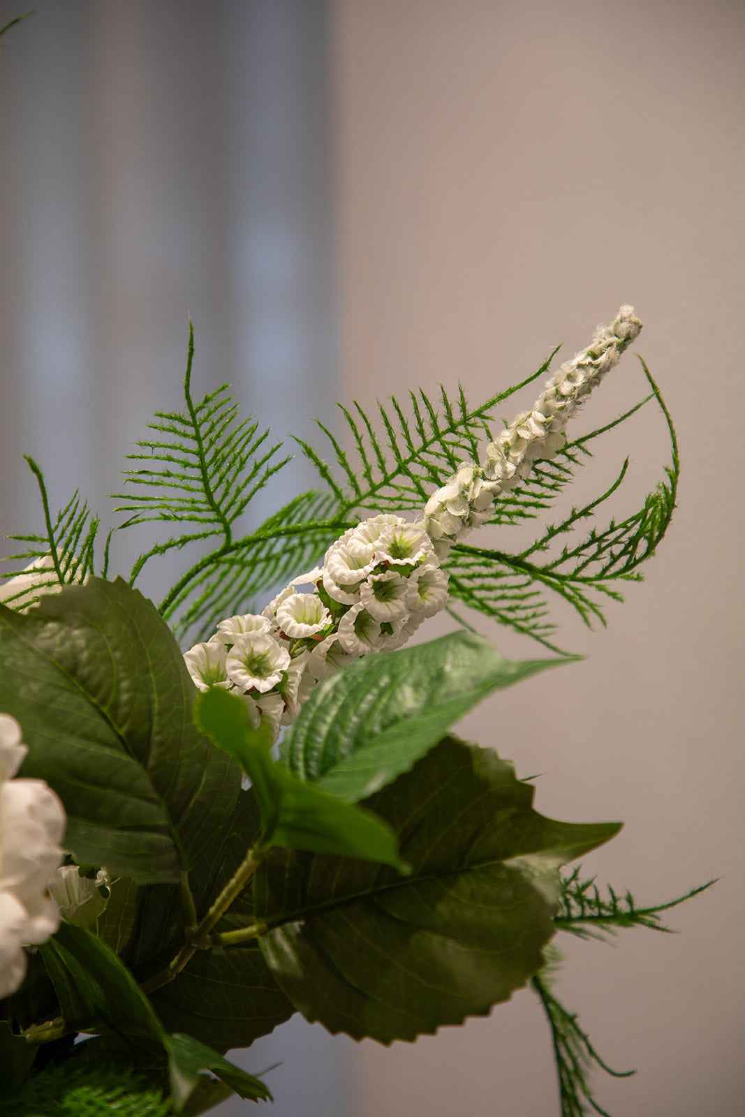 Nærbillede af hvide og grønne kunstige stilke, der er en del af en større buket.