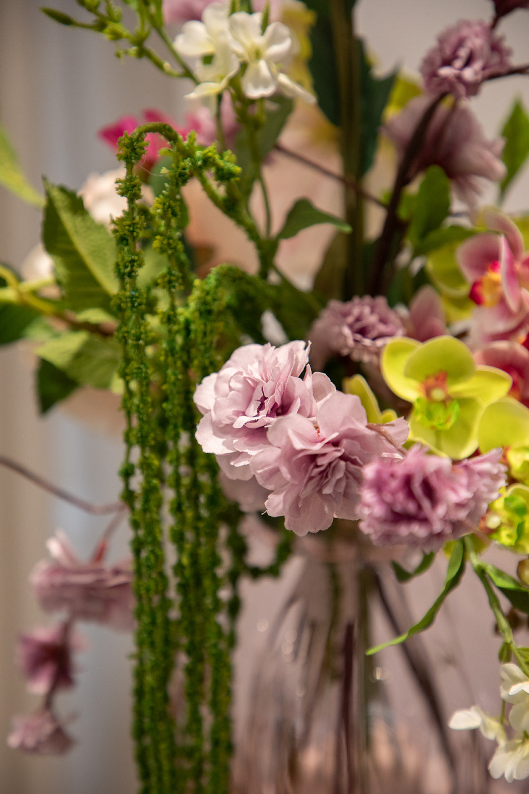 Nærbillede af buket af kunstige i grønne, lilla nuancer. 