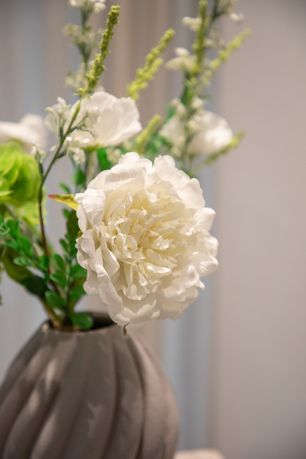 Nærbillede af buket af kunstige blomster i hvide og grønne nuancer. 