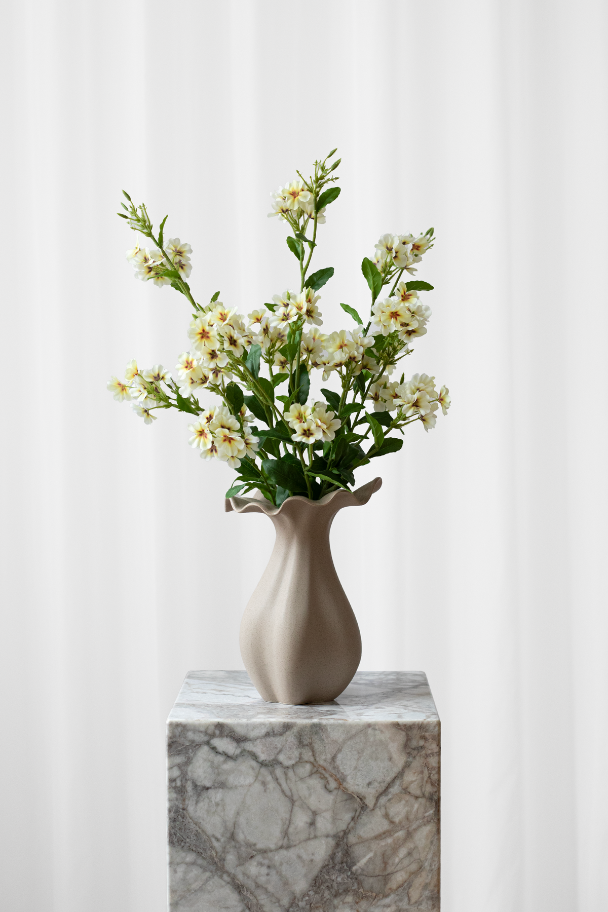 Buket af kunstige, lysegule blomster, der ser ægte ud.