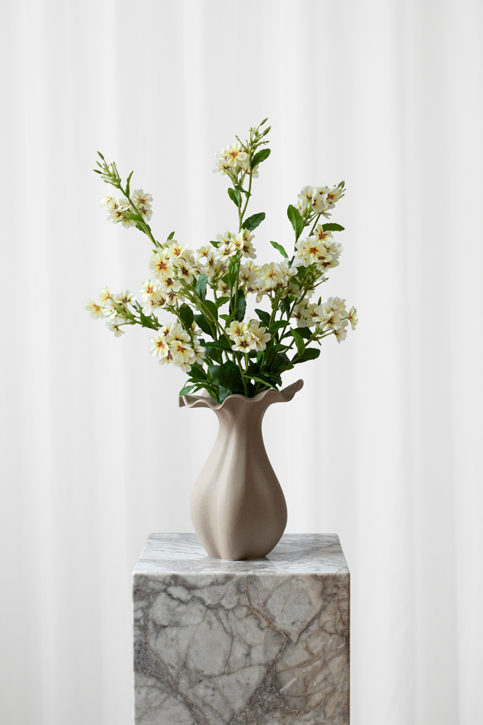 Buket af kunstige, lysegule blomster, der ser ægte ud.