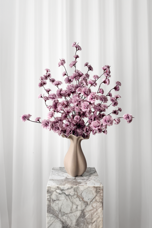 Buket af lilla kirsebærgrene stylet i en keramikvase. Blomsterne er naturtro kunstige blomster fra Specktrum.