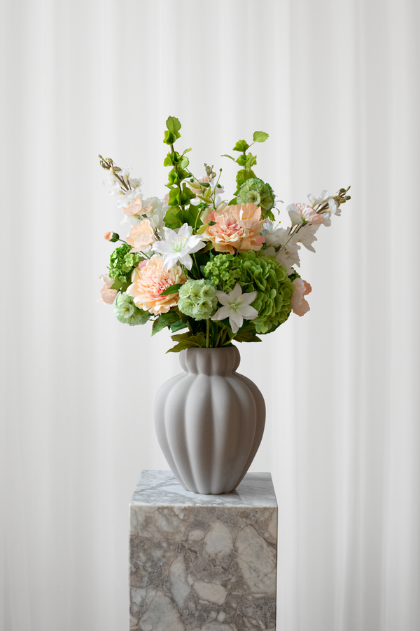 Sommerlig buket i ferskenfarvede, orange, grønne og hvide nuancer. Buketten er skabt af kunstige blomster med naturtro detaljer. 