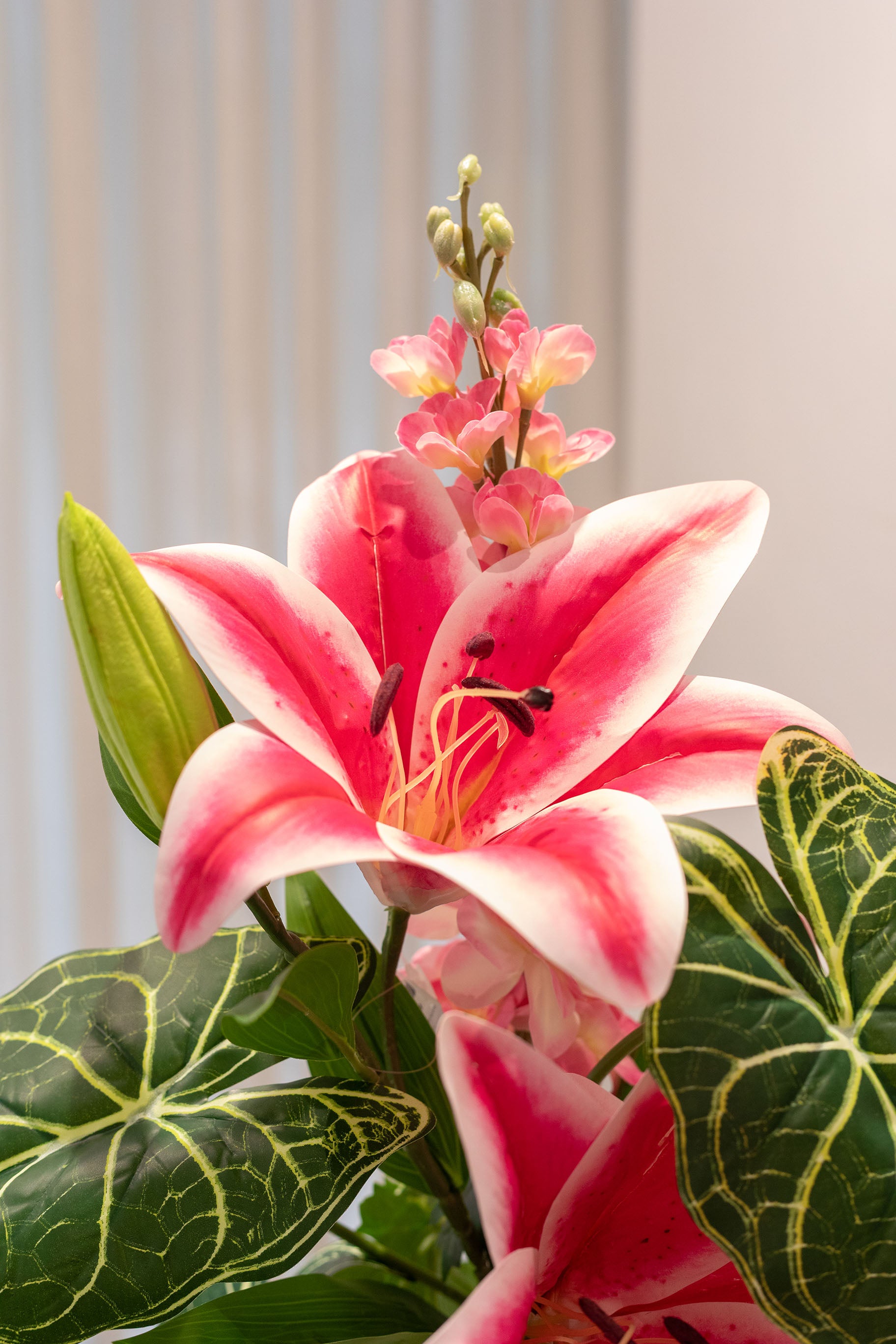 Nærbillede af buket af kunstige blomster i lyserøde og grønne nuancer.