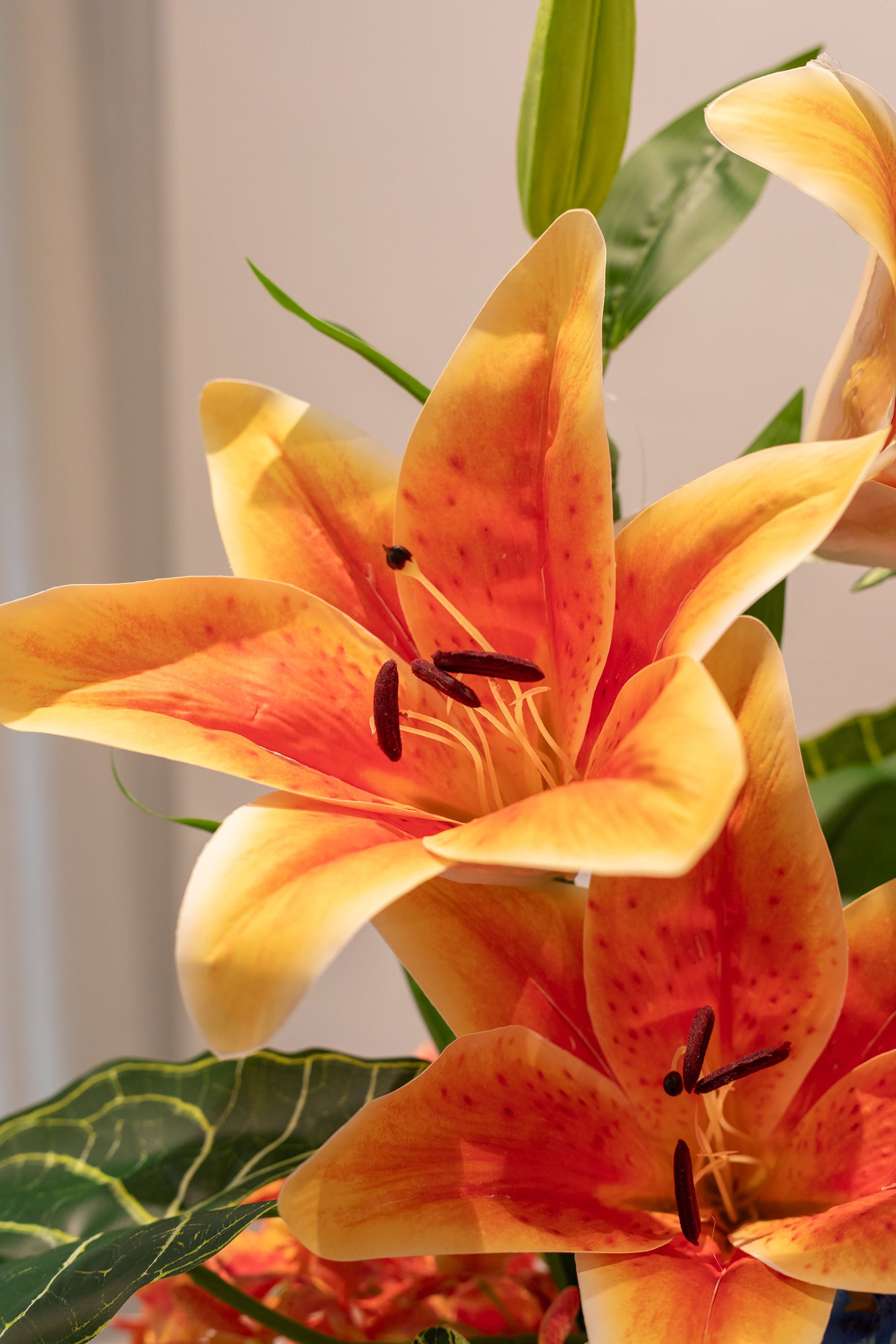 Nærbillede af stor orange lilje. En del af en buket i grønne, orange og blå nuancer.