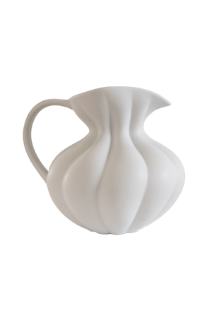 Hvid keramisk kande med bløde, bølgende former og rund hank, vist mod hvid baggrund.