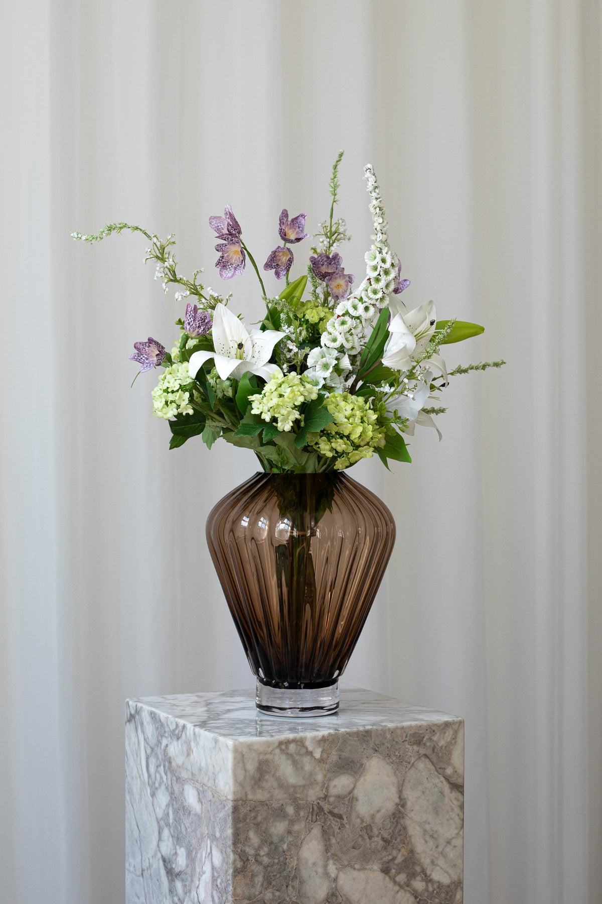 Buketten til den du elsker er skabt af liljer, hortensia og klokkeblomster i grønne, hvide og lilla nuancer.