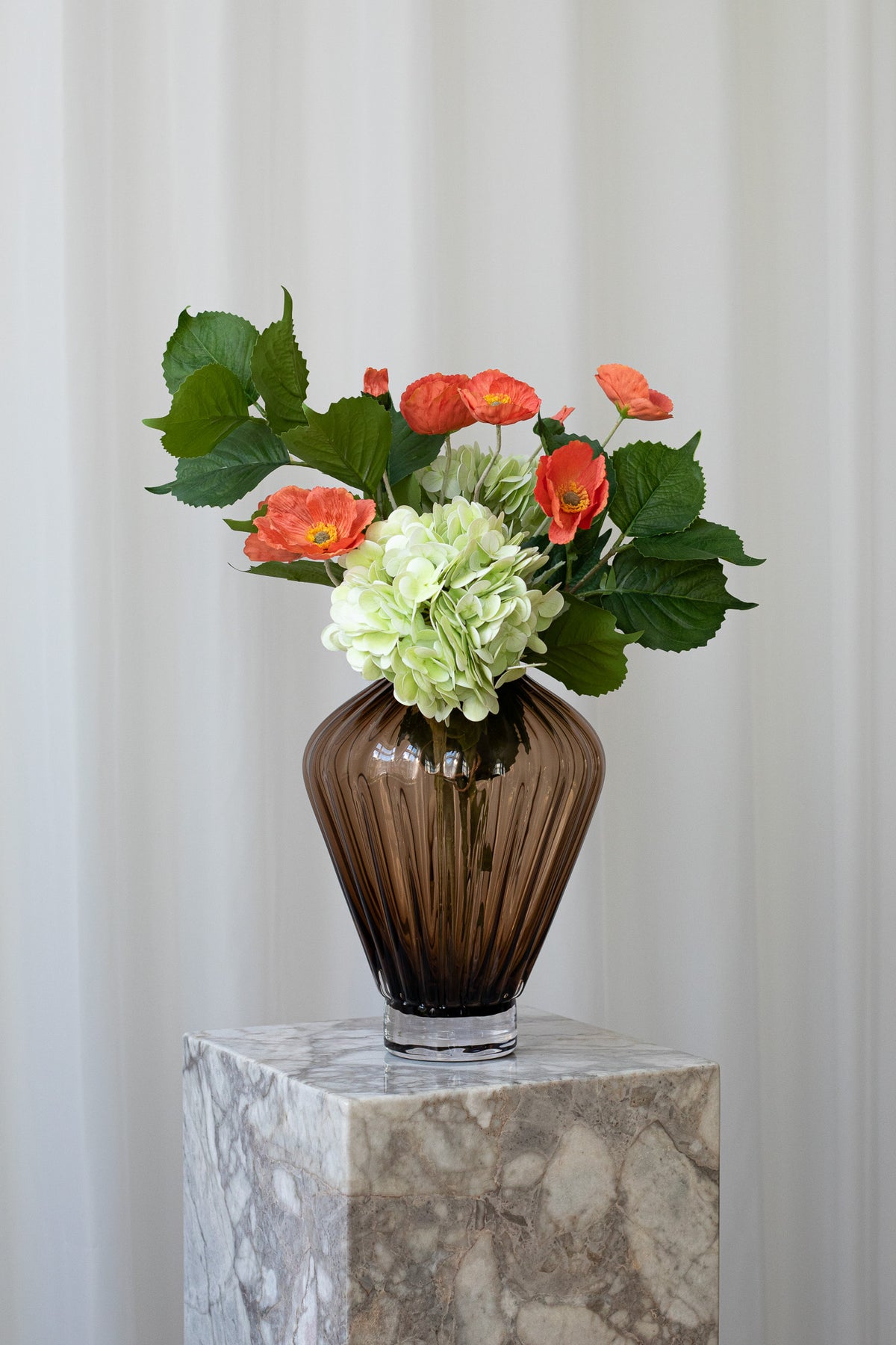 En kunstig buket, der siger "Jeg er her for dig" med hortensia, valmuer og bladgrene i grønne og rødlige farver.
