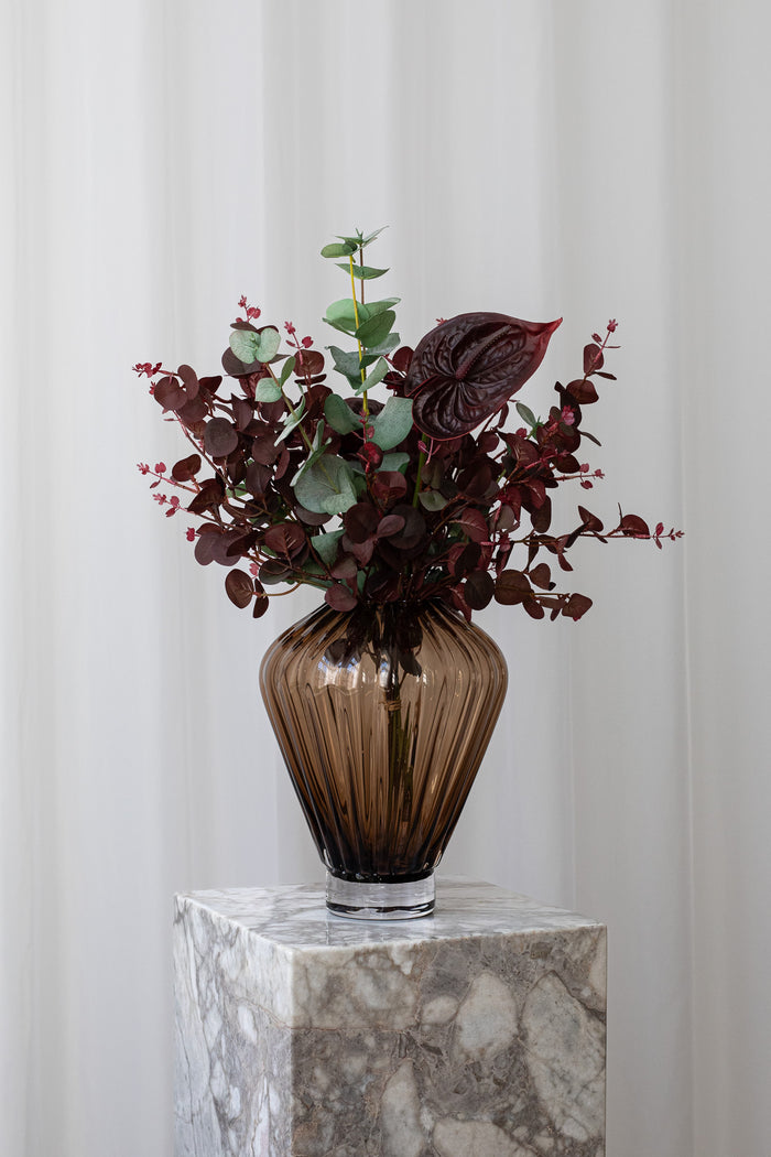 Kunstig buket fra Specktrum, der viser en særlig person, at du savner dem. Buketten er i dramatiske bordeaux farver, og indeholder eukalyptus og flamingoblomster.