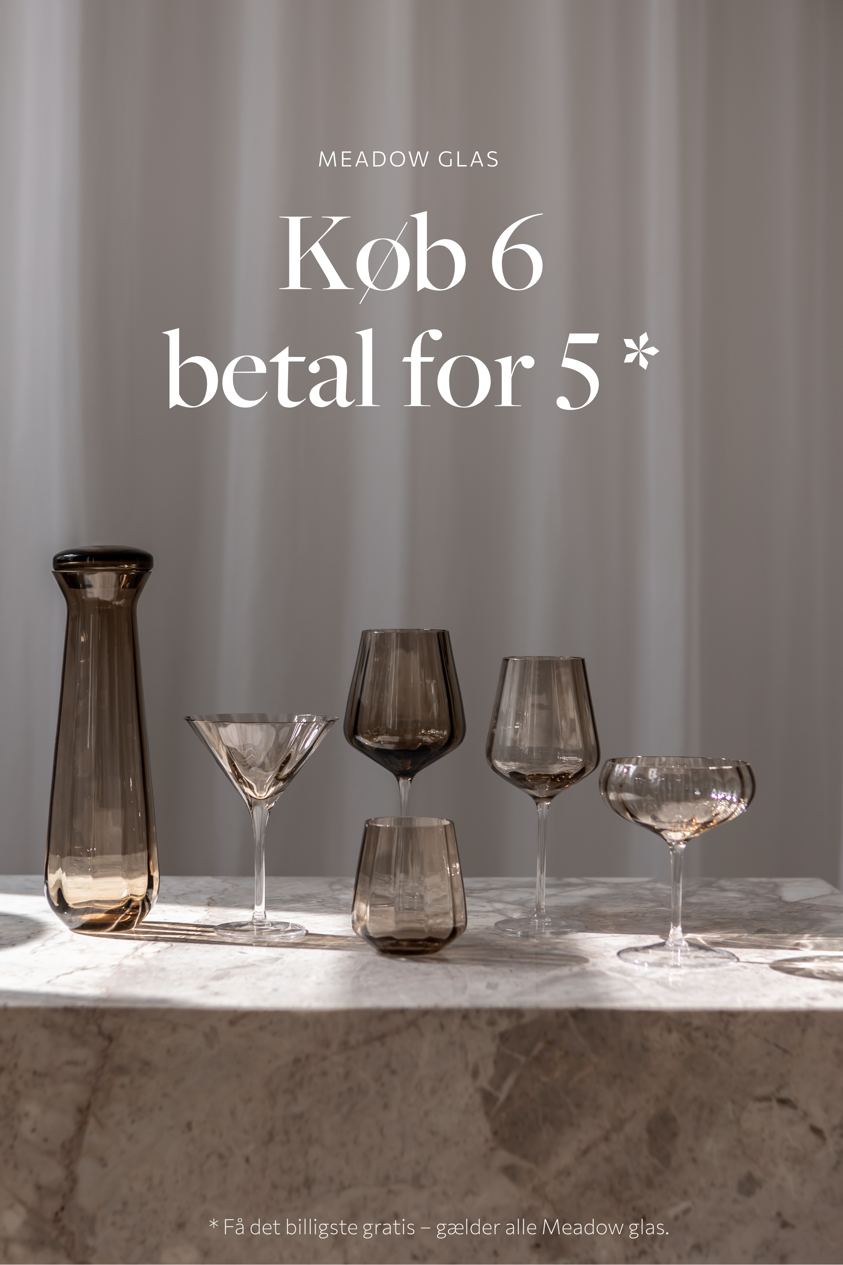 : En kampagneplakat med teksten "MEADOW GLAS – Køb 6 betal for 5*". På et marmorbord står en røgfarvet karaffel sammen med fem forskellige glas: et cocktailglas, et vinglas, et hvidvinsglas, et lavt drikkeglas og et coupe-glas. Nederst står med småt: "*Få det billigste gratis – gælder alle Meadow glas."