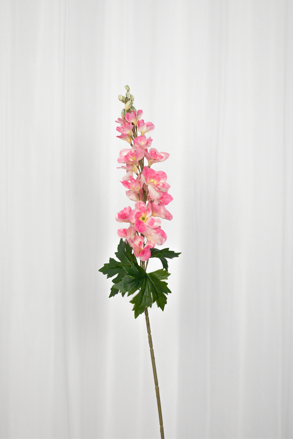 Kunstig consoldia i en rosa farve med grønne blade i bunden.