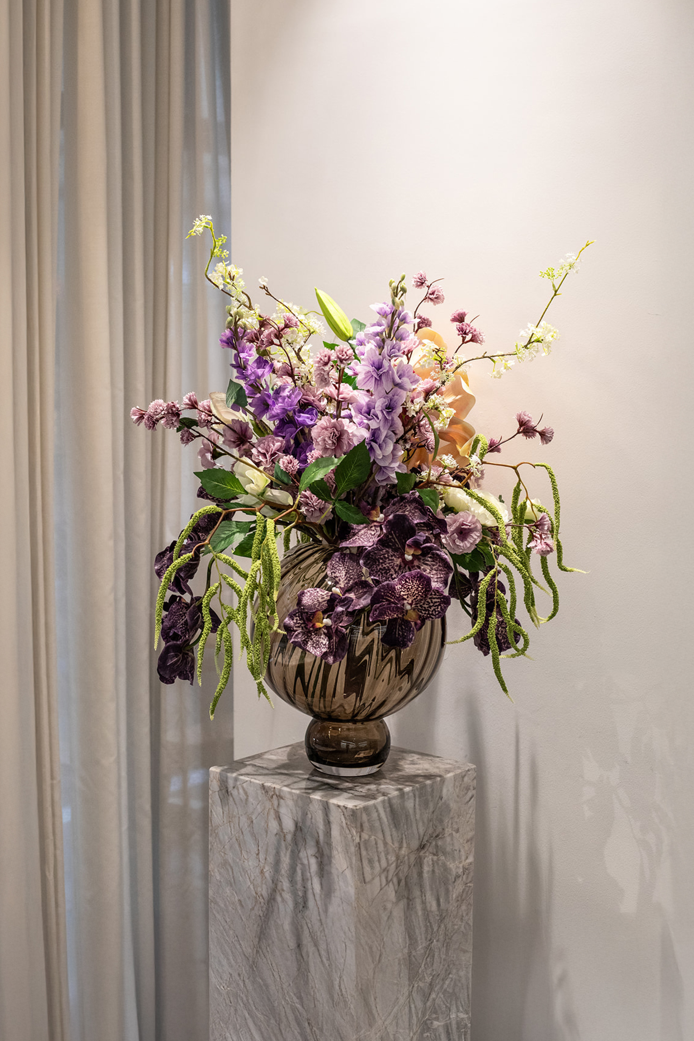 Kunstige blomster sammensat til en overdådig buket. Buketten er stylet i Meadow swirl vasen i farven topaz i large. 