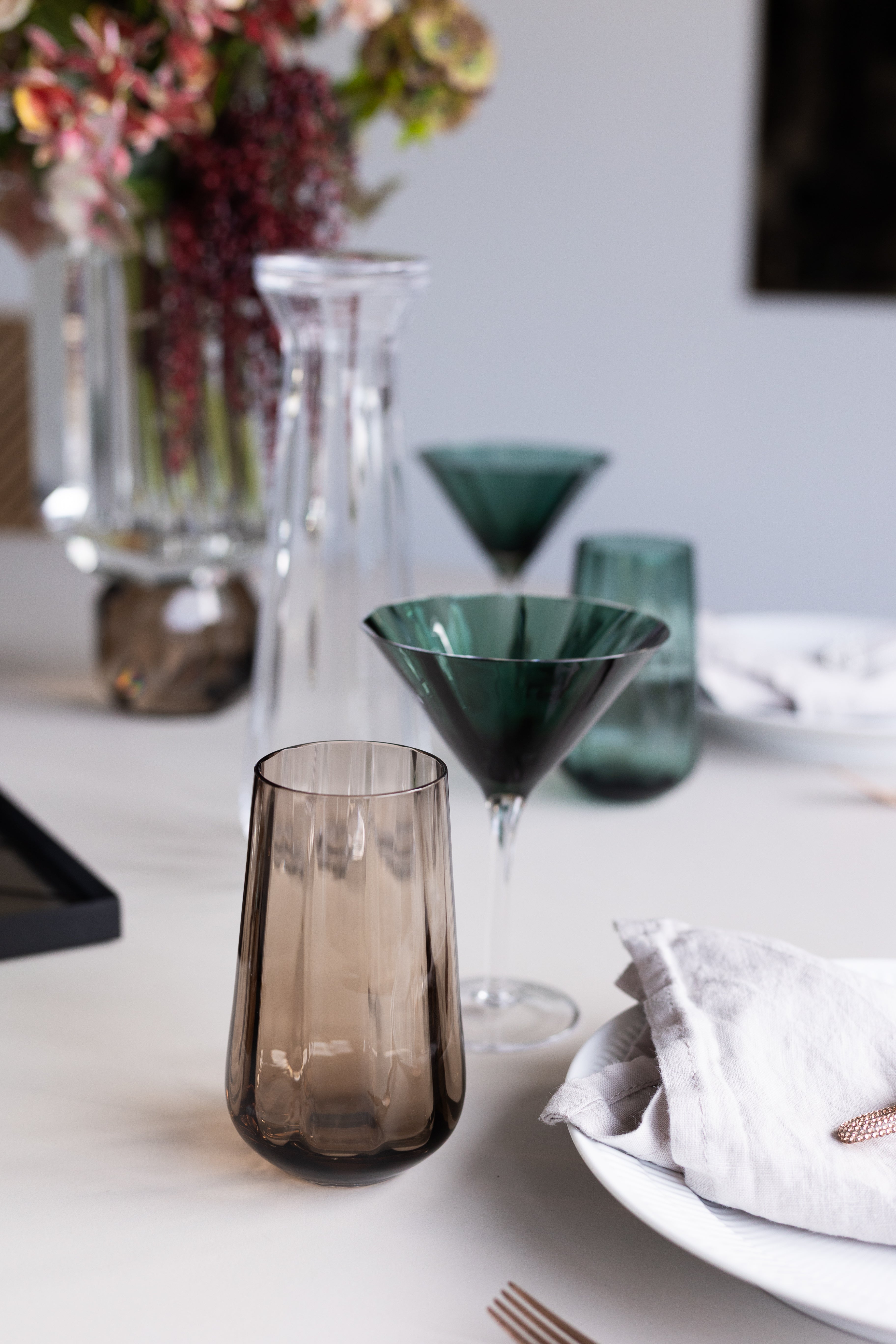 Højt drikkeglas i serien Meadow fra Specktrum. Glasset er stylet med klare og grønne glas designs fra samme serie på et spisebord.