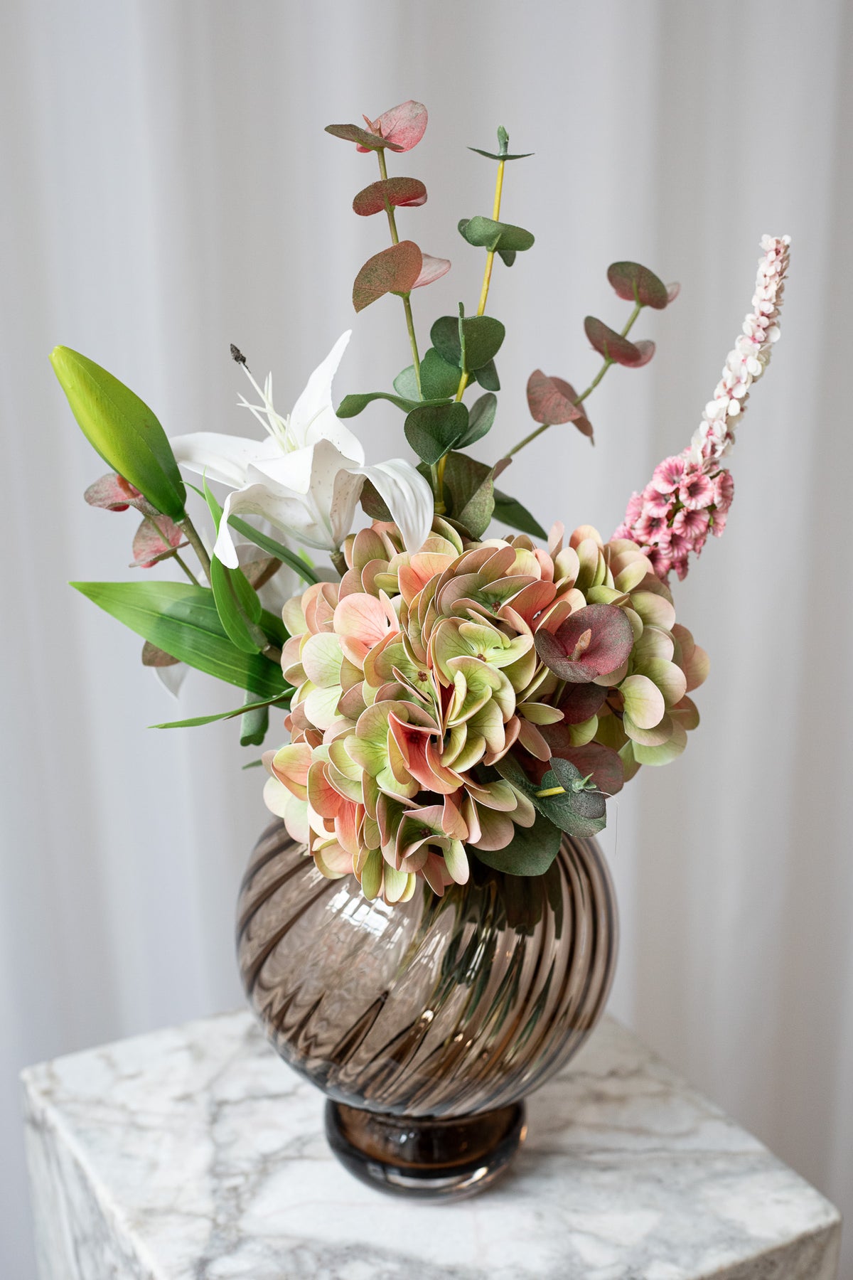 Nærbillede af den naturtro, kunstige buket med hortensia, eukalyptus og liljer.