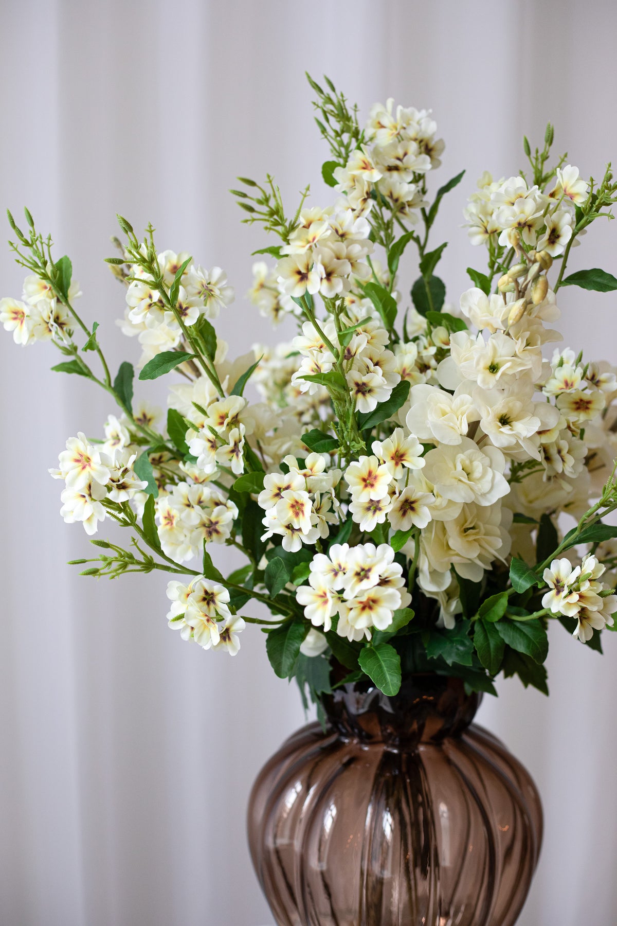 En kunstig buket i lyse gule farver og grønt. Blomsterne føles naturlige.