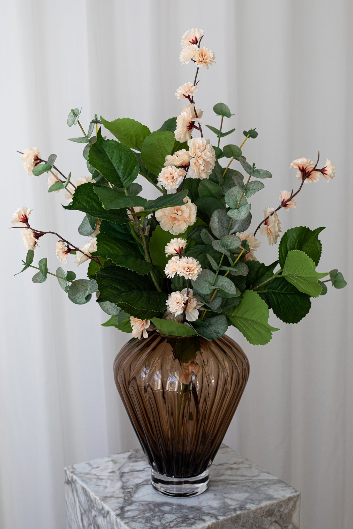 Buket med eukalyptus, kirsebærgrene og bladgrene, stylet i en mundblæst glasvase fra Specktrum.