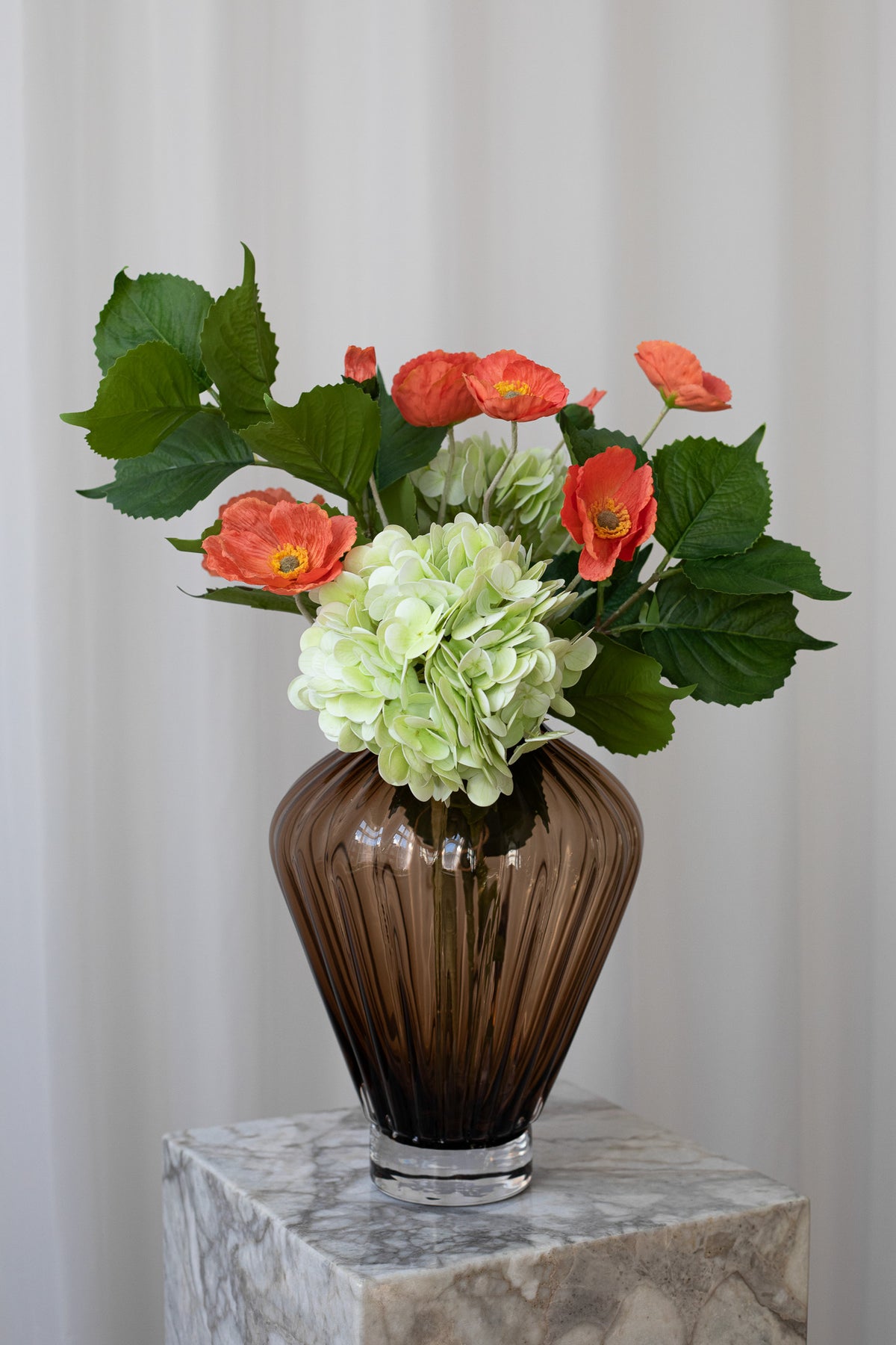 Nærbillede af en medium størrelse buket af kunstige stilke fra Specktrum. Buketten har valmuer, hortensia og bladgrene, der giver en luftig buket. 
