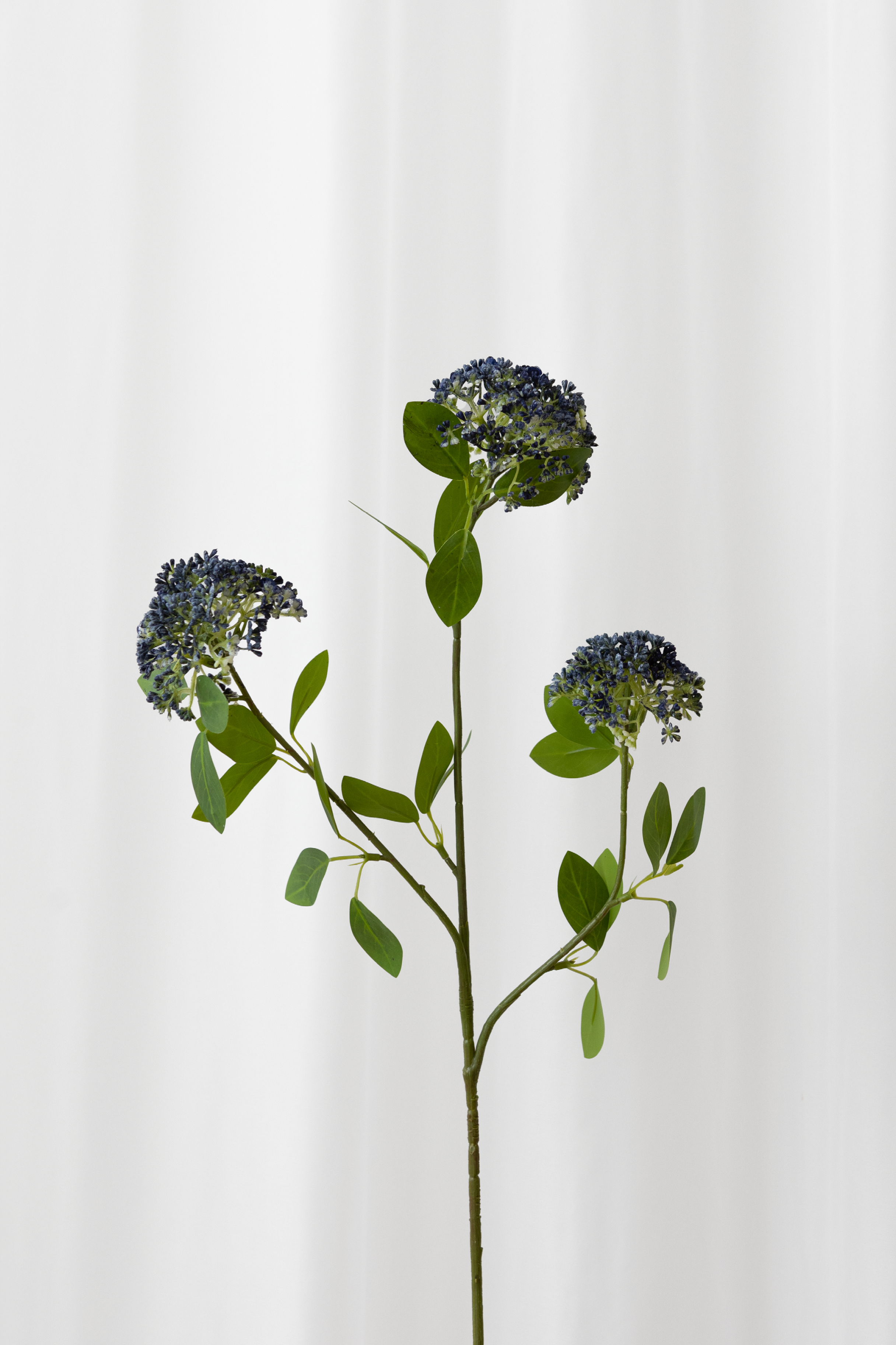 Naturtro kunstig bærgren med tre hoveder med blå blomster og grønne blade med høj detaljegrad. Naturtro blomster til konkurrencedygtige priser.