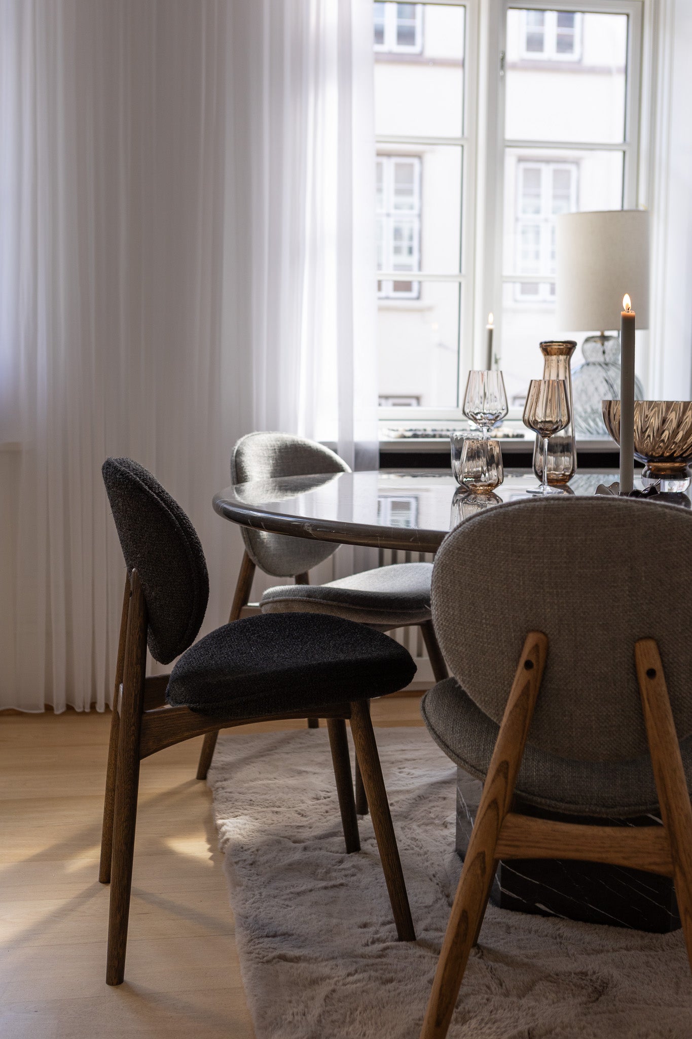 FSC-certificeret spisebordsstol fra Specktrum i mørkolieret egetræ med sort polstring. Placeret ved et marmor spisebord, med bordopdækning fra Specktrum. 