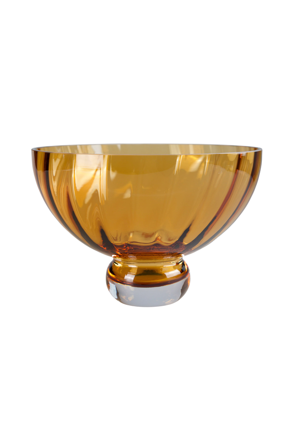 Ravfarvet Meadow skål i glas med rund fod. Skålen har et elegant, mundblæst udtryk og en varm gylden tone, der reflekterer lyset.