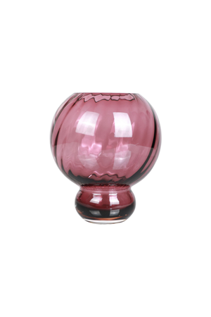 En mundblæst glasvase i dyb pink farve med en rund form og kort fod. Glasset har en swirl-struktur, der giver et levende lys- og skyggeudtryk. Vasen står frit mod en hvid baggrund.