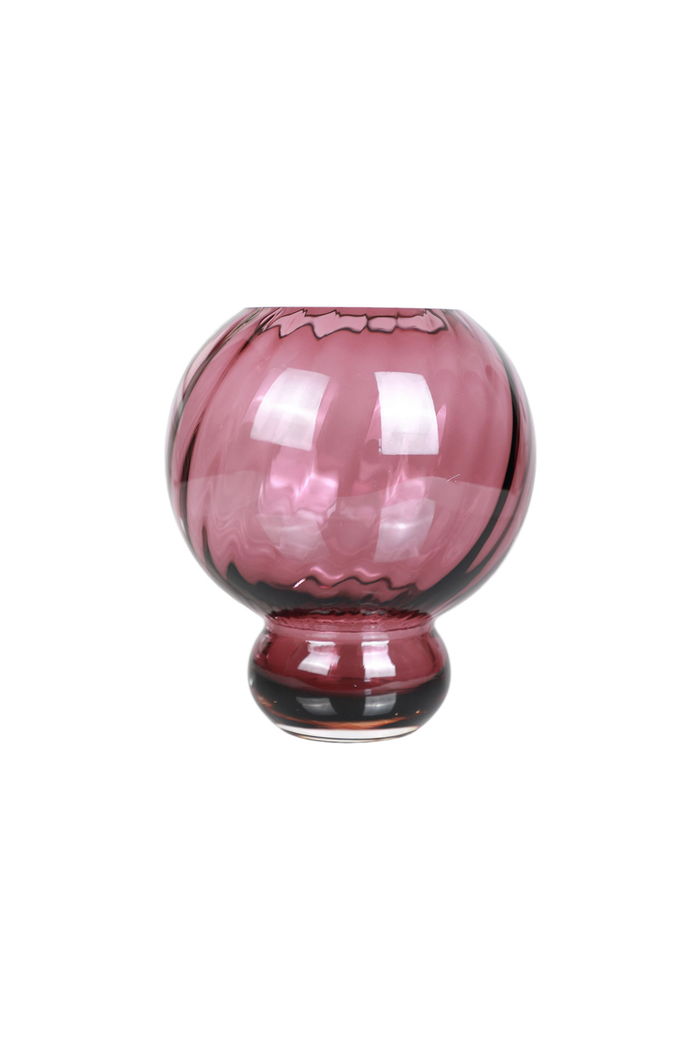 En mundblæst glasvase i dyb pink farve med en rund form og kort fod. Glasset har en swirl-struktur, der giver et levende lys- og skyggeudtryk. Vasen står frit mod en hvid baggrund.