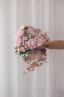 Brudebuket sammensat af kunstige blomster i farvenuancen lyserød.