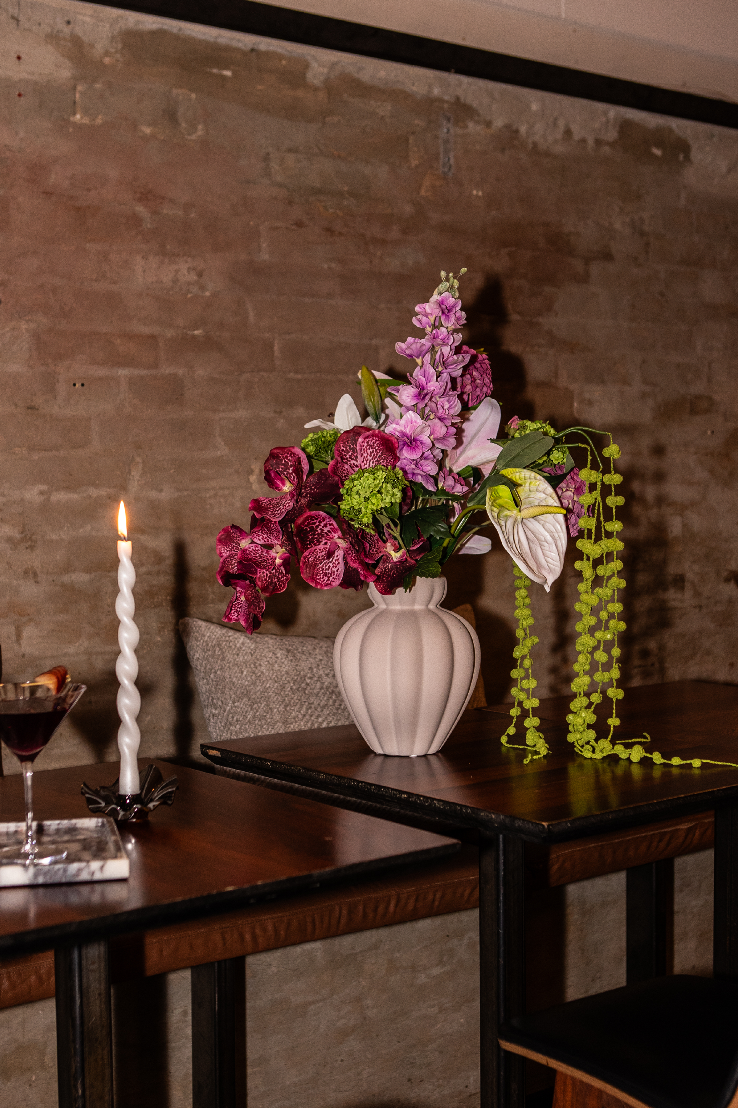 Penelope vase med kunstig buket stående på et bord på en restaurant. 