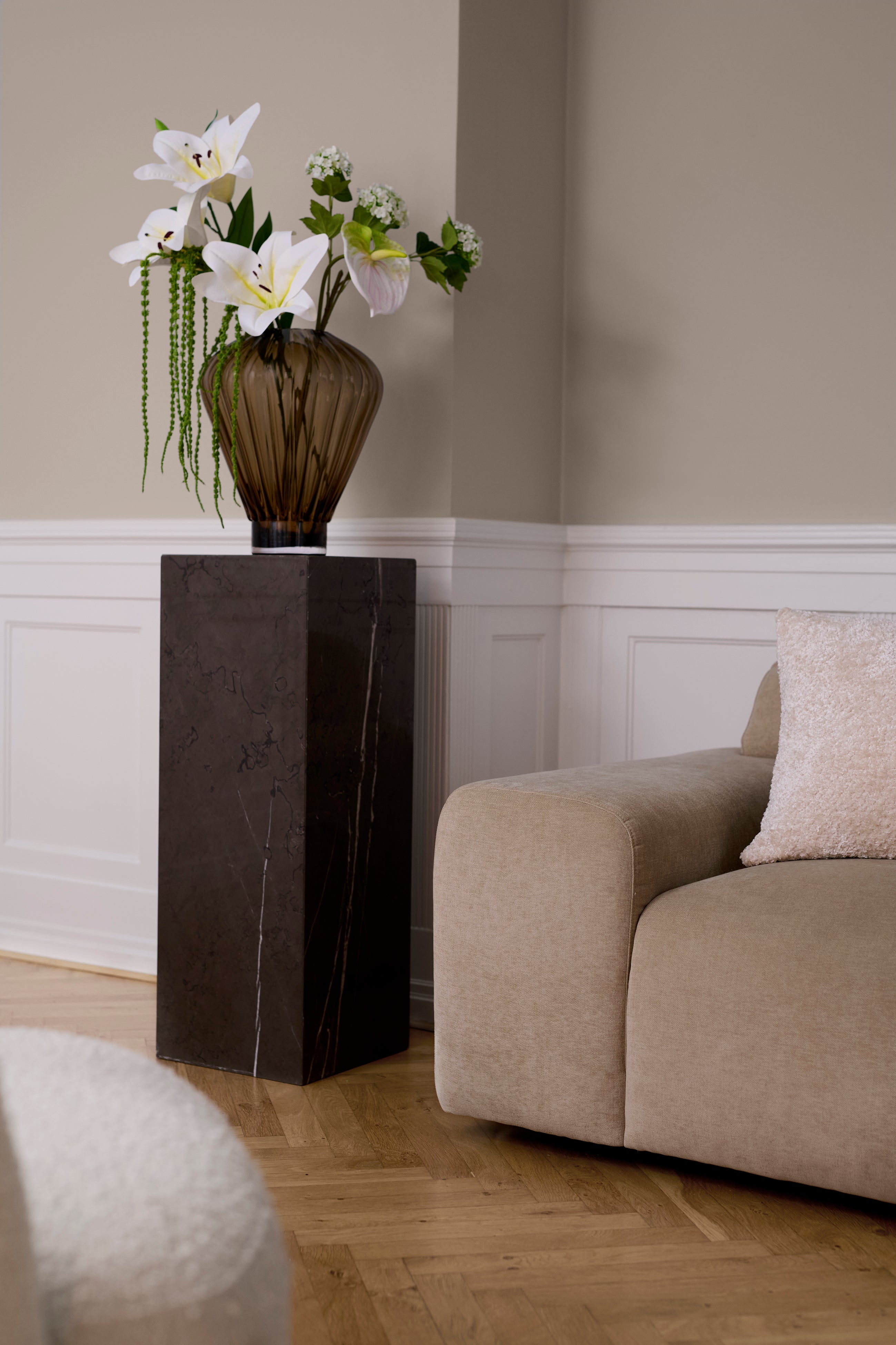 Phantom pedestal I farven lightning stylet i en stue med en Evelyn vase og buket ovenpå.