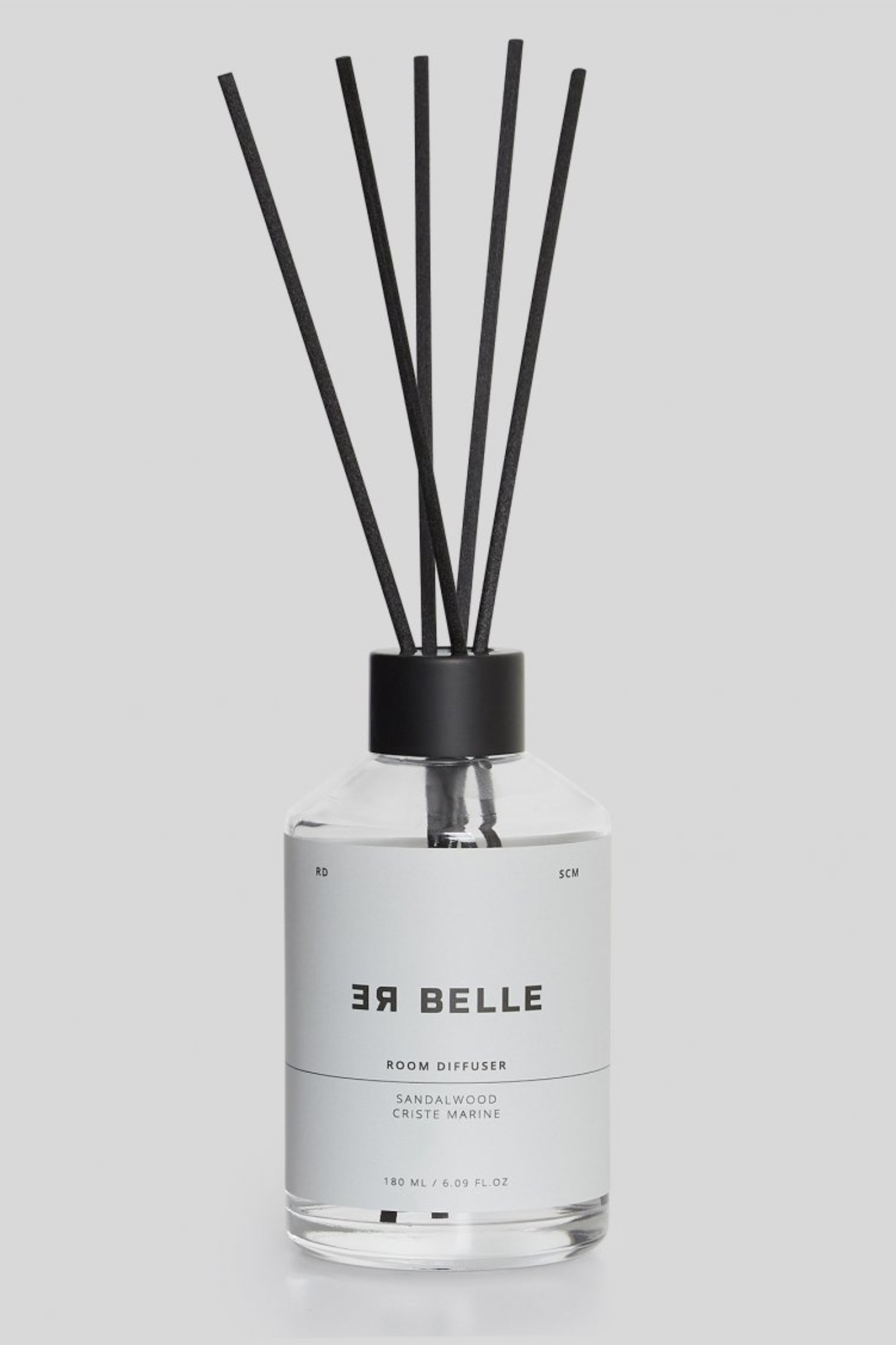 En gennemsigtig glasflaske med sort låg og flere sorte duftpinde. Etiket i hvidt med sort tekst: “ER BELLE ROOM DIFFUSER, SANDALWOOD, CRISTE MARINE, 180 ML