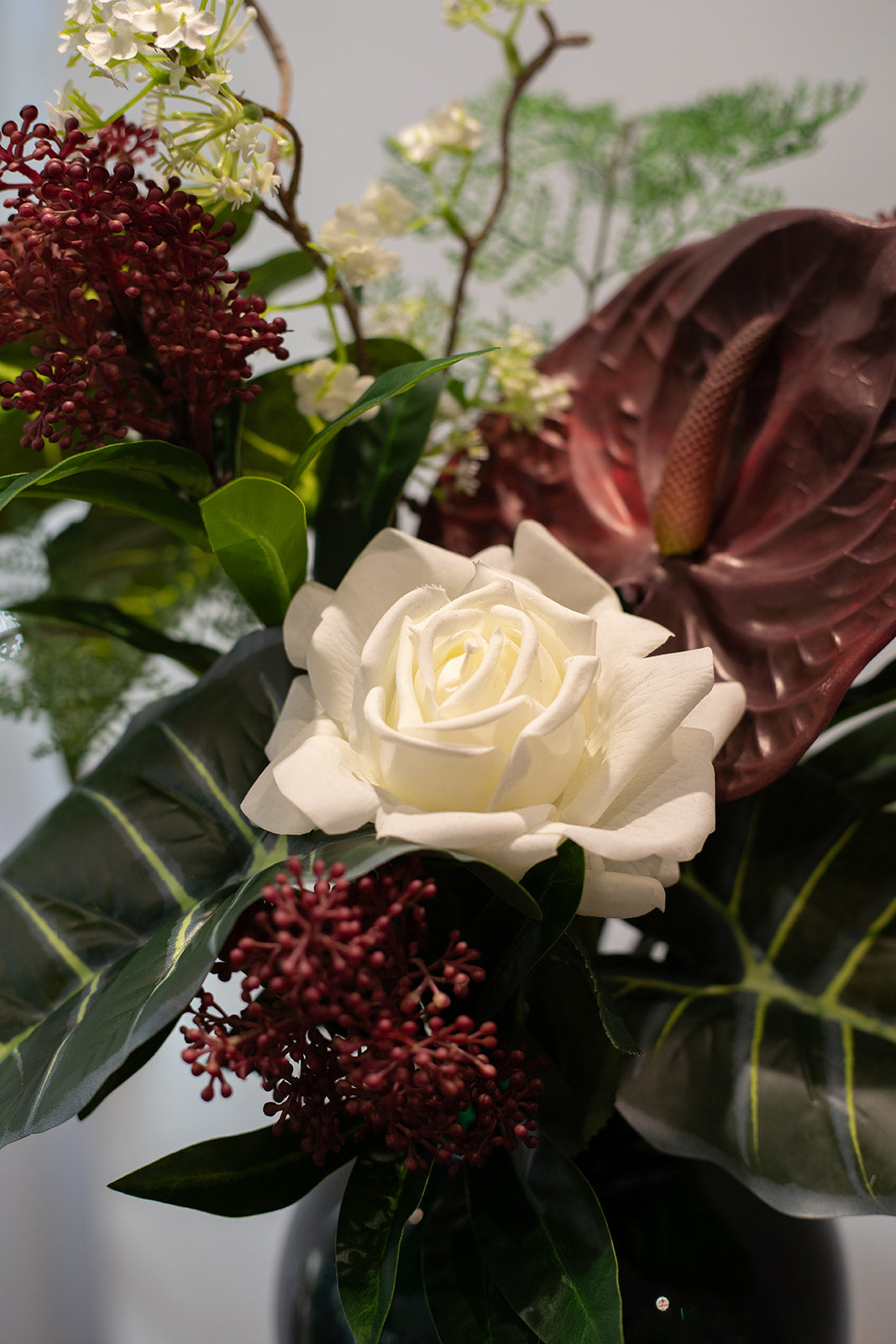 Nærbillede af hvid rose, del af en større buket i røde, hvide og grønne nuancer.