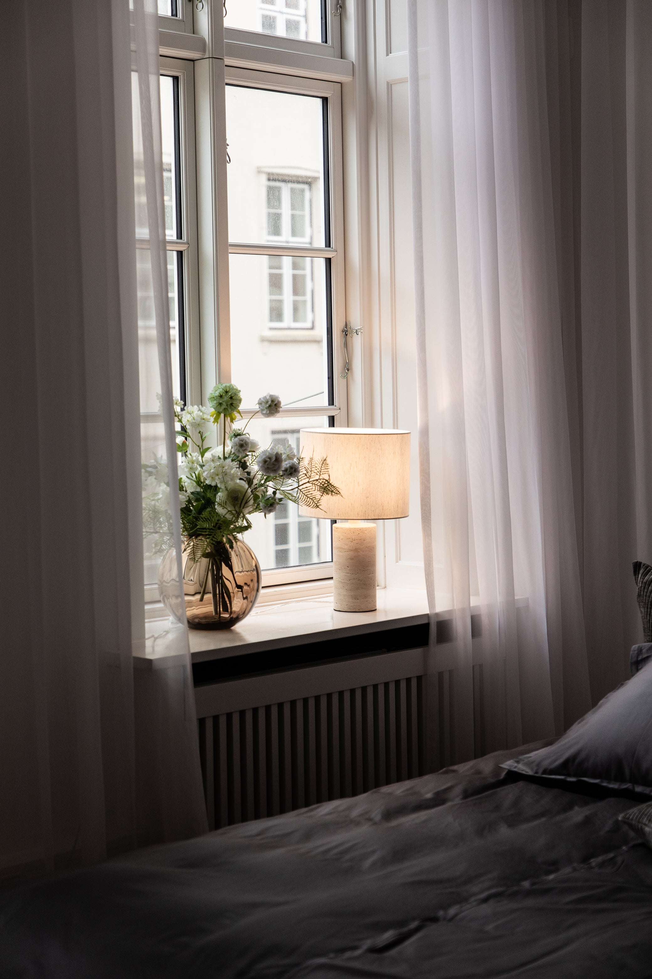 Bordlampe stylet med Sylvester lampeskærmen i hvid i en vindueskarm i soveværelset.