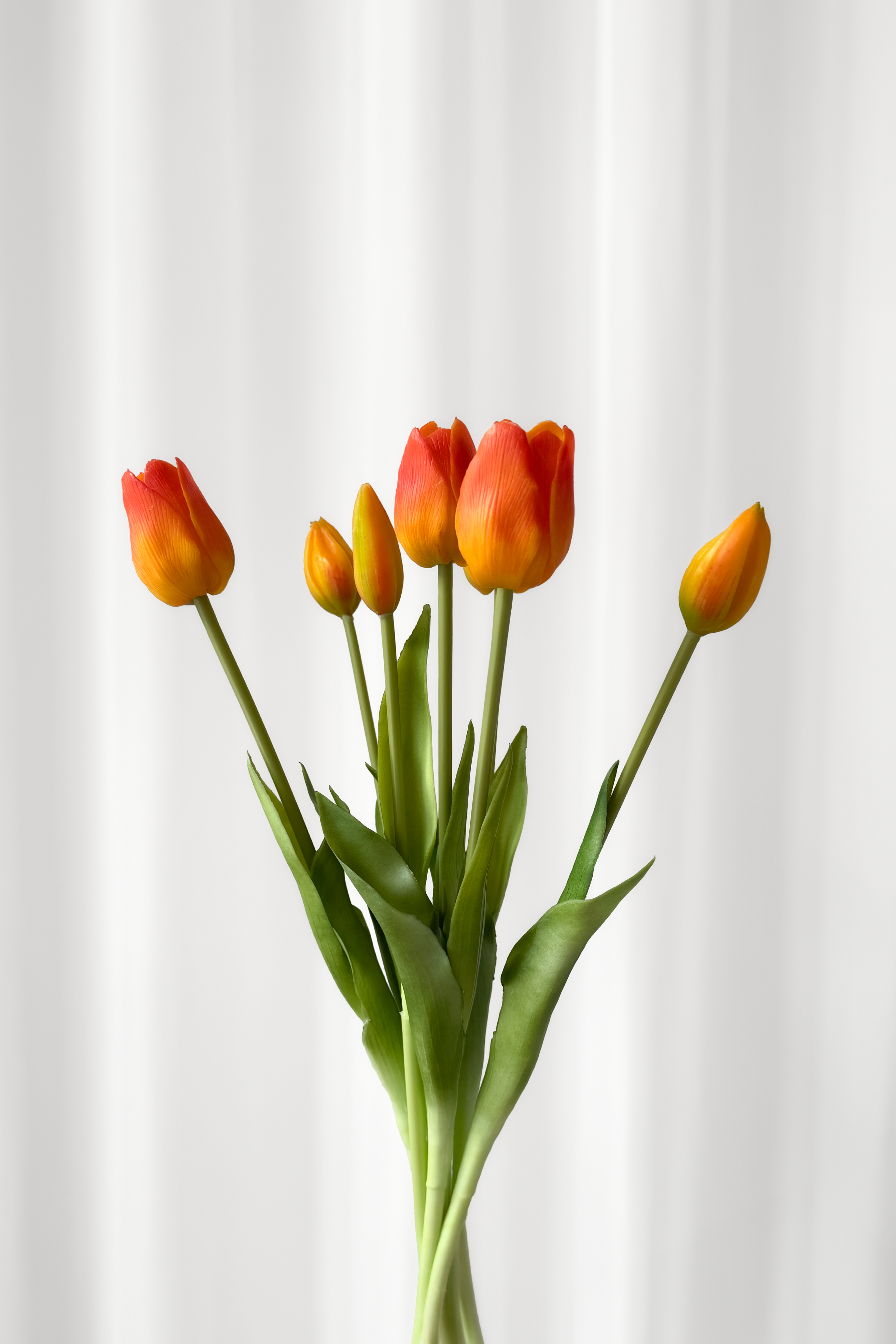 Bundt af kunstige tulipaner, der ser naturtro ud. Tulipanerne er orange.