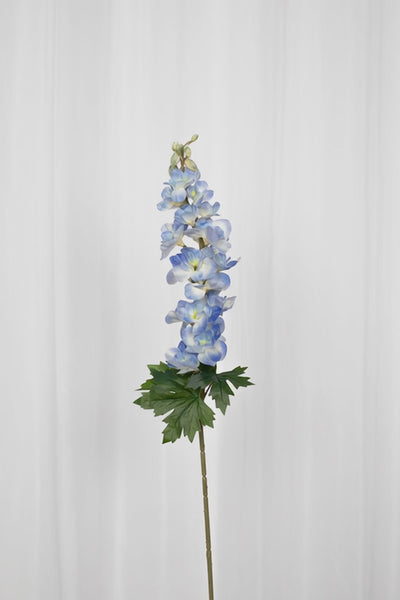 Video af Kunstig consolida blomst i blå med grønne blade i bunden. 