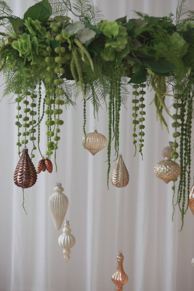 Video af en stor grøn krans af kunstige blomster, fra den hænger julekugler.