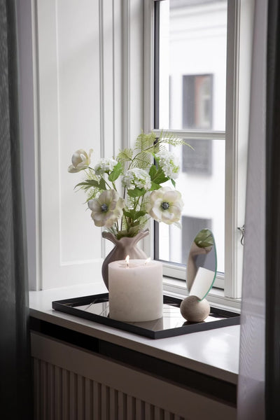Video af herringbone bakke, der står i en vindueskarm. På bakken står et connor lys, et bordspejl og en sand farvede nellie vase med kunstige blomster i.