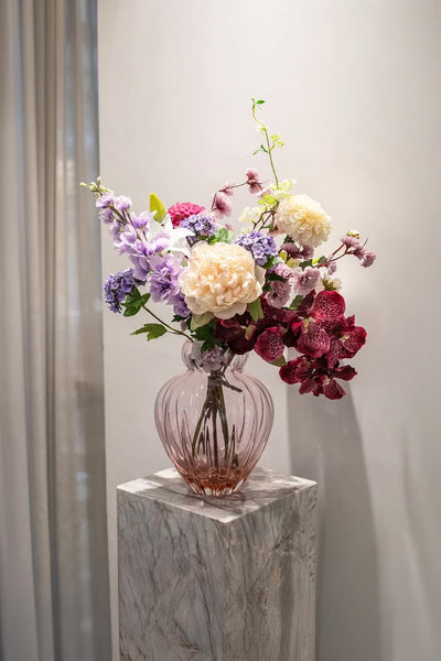 Kunstige blomster sammensat til buket. Buketten er stylet i Audrey i farven blossom i large.
Buketten indeholder: 
1 x Purple Cherry Blossom branch 
1 x White Fontanesia
1 x Pink Dahlia
1 x Creme Dahlia
1 x Creme Peony
1 x Light Purple Consolida
1 x White Lily small
1 x White Anthurium
1 x Plum Orchid (7 heads)
1 x Purple Hydrangea branch 