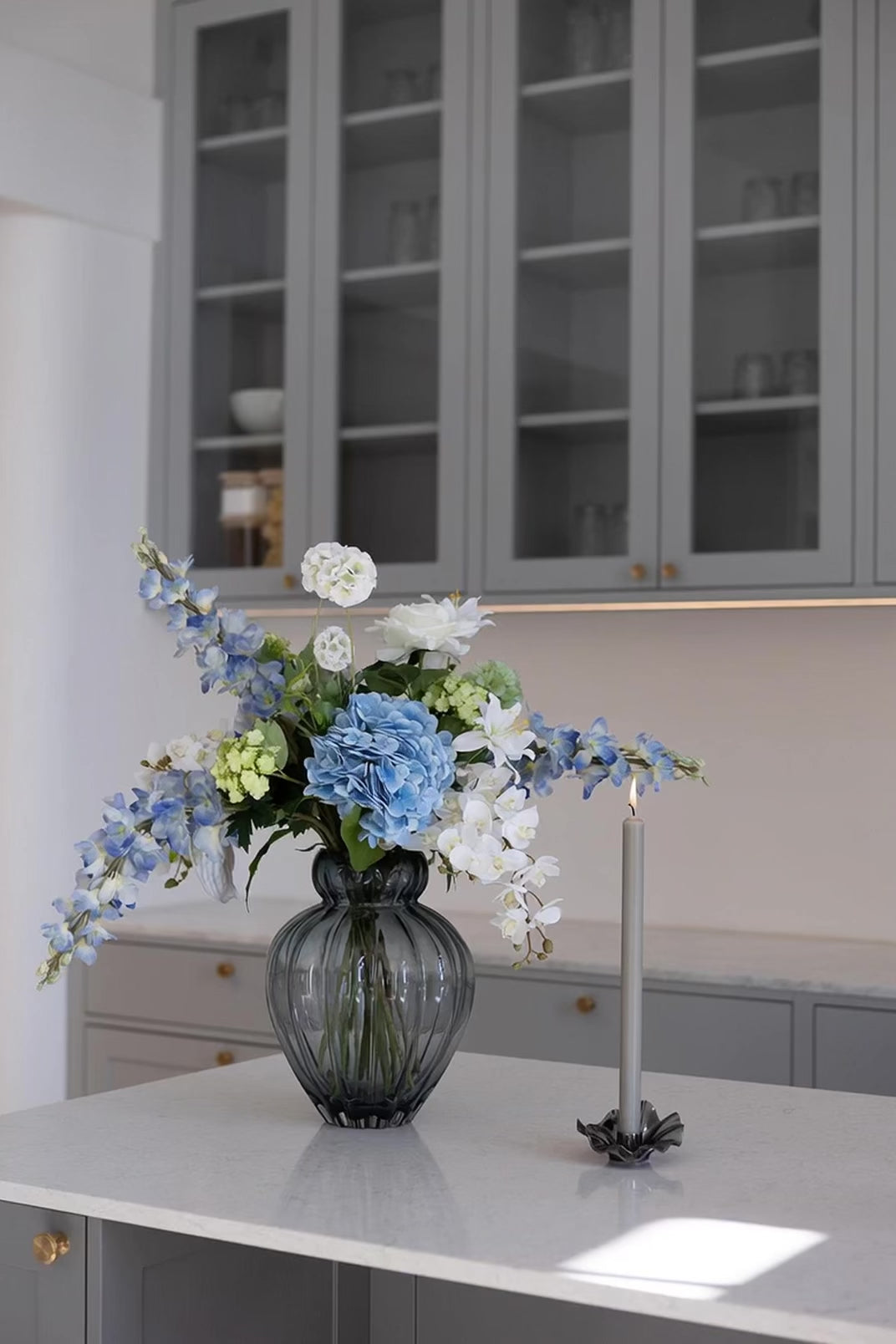 Video af Audrey vase i blå, med en buket i blå, grønne og hvide nuancer. Står på et køkkenbord med en lysestage og levende lys ved siden af.