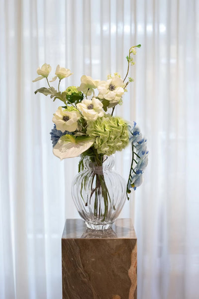 Kunstige blomster sammensat til en buket. Buketten er stylet i den mundblæste Audrey vase i large.
Buketten indeholder
1 x white anthurium
1 x light green hydrangea
1 x blue orchid (9 heads)
2 x white poppy 
1 x blue hydrangea
1 x white fontanesia 
1 x light green hydrangea branch