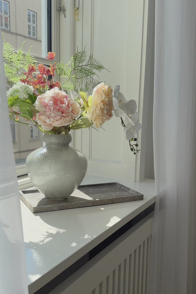 Video af phantom marmorbakke i farven thunderstorm, der står i en vindueskarm. På bakken står en stor glasvase med kunstinge blomster i.