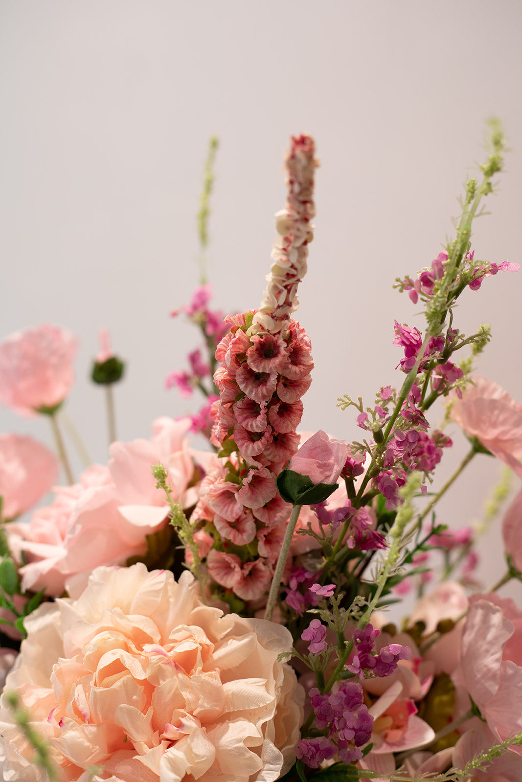 Nærbillede af stilke i en større kunstig buket i lyserøde og rosa nuancer.